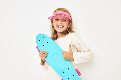 Portrait of smiling young woman holding tape measure against white background