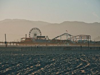 Mid distance view of amusement park against clear sky during sunset