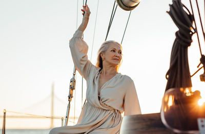 Low angle view of senior woman looking away against sky