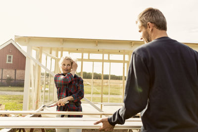 Man assisting woman in making shed at farm