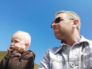 Low angle view of man and sunglasses against clear sky