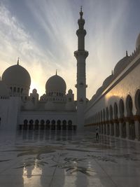 Grand mosque against cloudy sky during sunset
