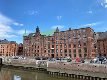 Buildings by river against sky