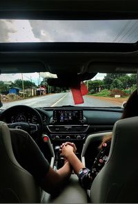 Man driving car on road seen through windshield