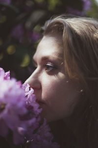 Close up woman smelling flowering shrub with pink flowers portrait picture