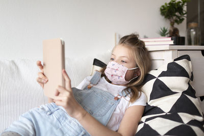 Girl using mobile phone on sofa at home