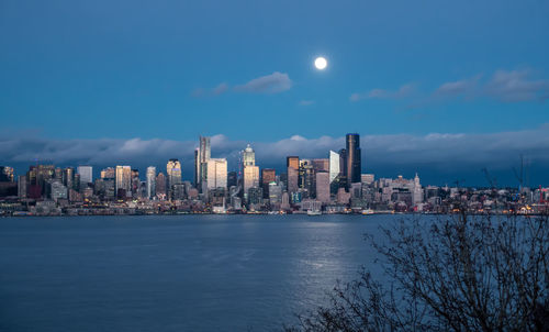 A full moon shines above the seattle skyline.