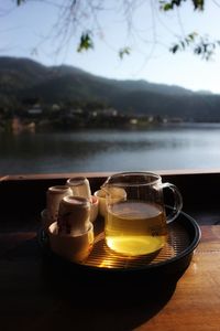 Close-up of drinks on table against lake