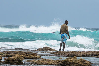 Rear view of men at beach against sky