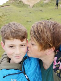 Mother kissing son while standing on field