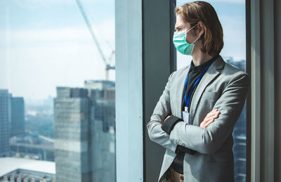 Young woman standing by window at office building