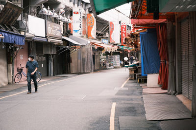 Rear view of people walking on street amidst buildings