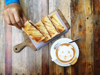 Cropped image of man having snack and cappuccino on table