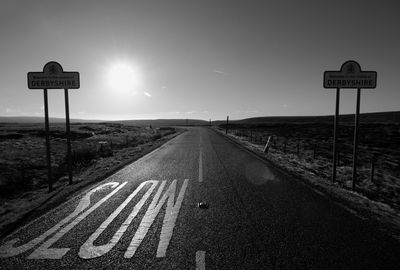 Close-up of slow sign on country road against sky suring sunny day