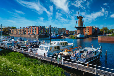 Sailboats moored on river in city against sky