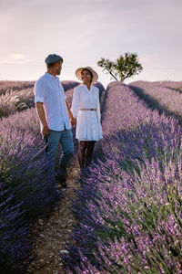 Full length of young woman standing on lavender against sky
