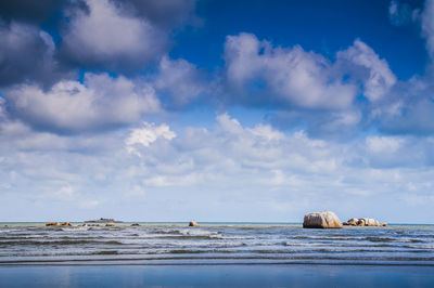 Scenic view of beach against cloudy sky