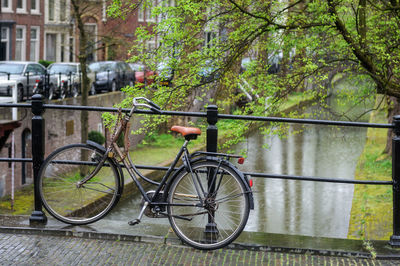 Bicycle parked on railing by river in city