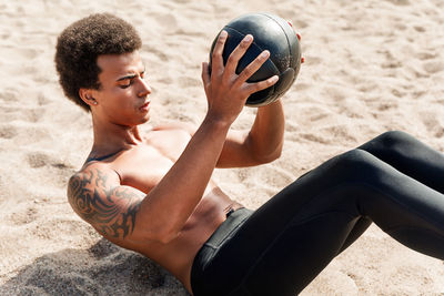 High angle view of man exercising with medicine ball at beach