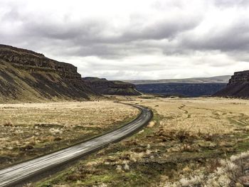 Scenic view of mountain road against cloudy sky