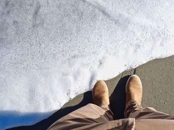 Low section of man standing on beach