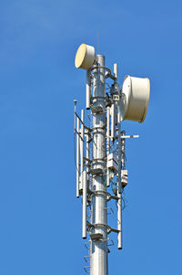 Low angle view of communications tower against clear blue sky