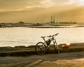 Bicycle parked on beach against cloudy sky