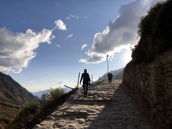 Rear view of woman walking on mountain against sky