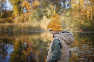 Man standing by lake in forest during autumn