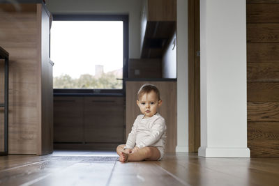 Portrait of cute boy sitting on floor at home