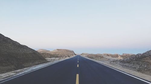 Road by mountains against clear sky