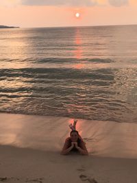 Portrait of woman lying at beach during sunset