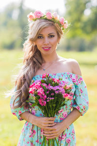 Portrait of beautiful young woman standing against pink flowering plants