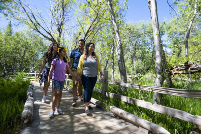 People walking on footbridge in forest