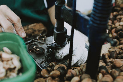 Cropped hands of person working on machine by nuts