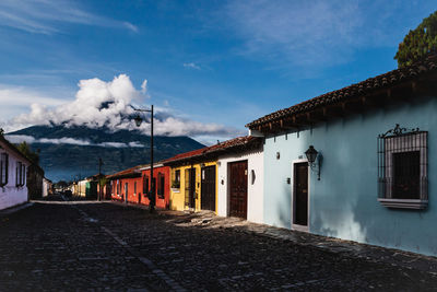 Diminishing perspective of road amidst houses against blue sky