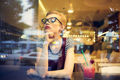 Young woman looking away while sitting in restaurant