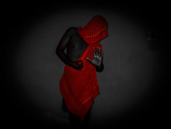 Midsection of woman wearing hat standing against black background