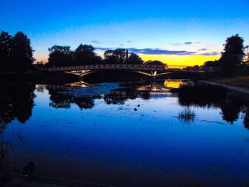 Bridge over river against sky at sunset