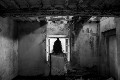 Rear view of woman standing in abandoned building