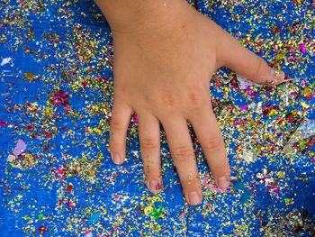 Cropped image of hand on confetti over table