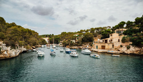 Sailboats moored on sea against sky in city