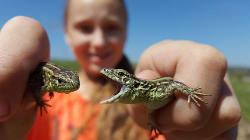 Close-up of girl holding two lizards