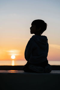 Beautiful orange sunset on the sea with the silhouette of a child in the background.