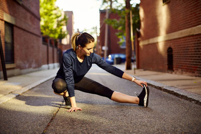 A female runner stretches on a city street.