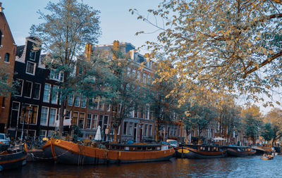 Boats moored in river by buildings against sky