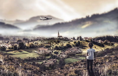 Rear view of woman standing on landscape against sky