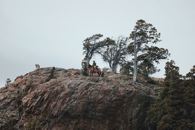 Low angle view of man standing on rock against clear sky