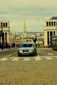 Cars on street in city against sky