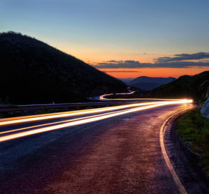 Light trails on road against sky during sunset